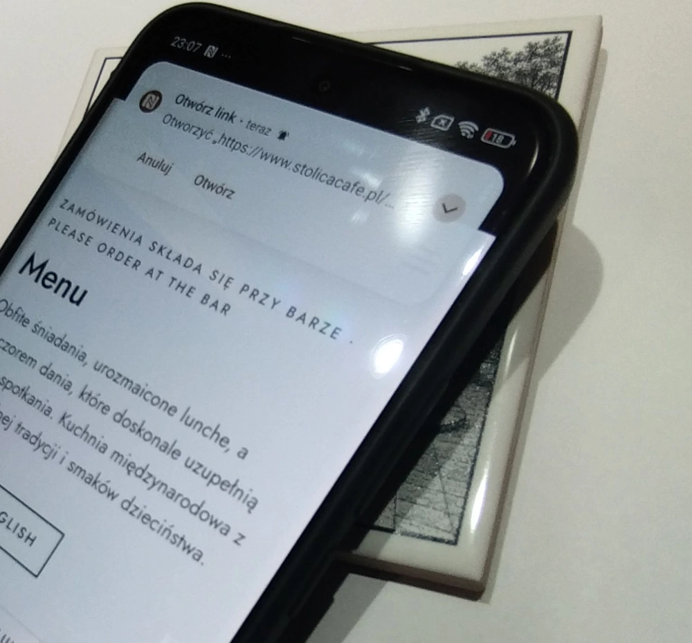 Telefon nad kaflem pokazuje link NFC do menu Stolica Café